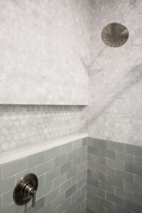 Shower detail with marble hexagon tile and grey subway tile niche