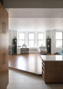 Modern live-work loft interior with custom walnut cabinetry and peninsula dining area in Chelsea, NYC.