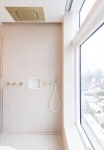 High-rise luxury shower featuring a ceiling-mounted showerhead and floor-to-ceiling window with cityscape views.