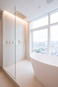 New York City high-rise minimalist bathroom with ceiling rainfall showerhead and large window overlooking urban landscape.