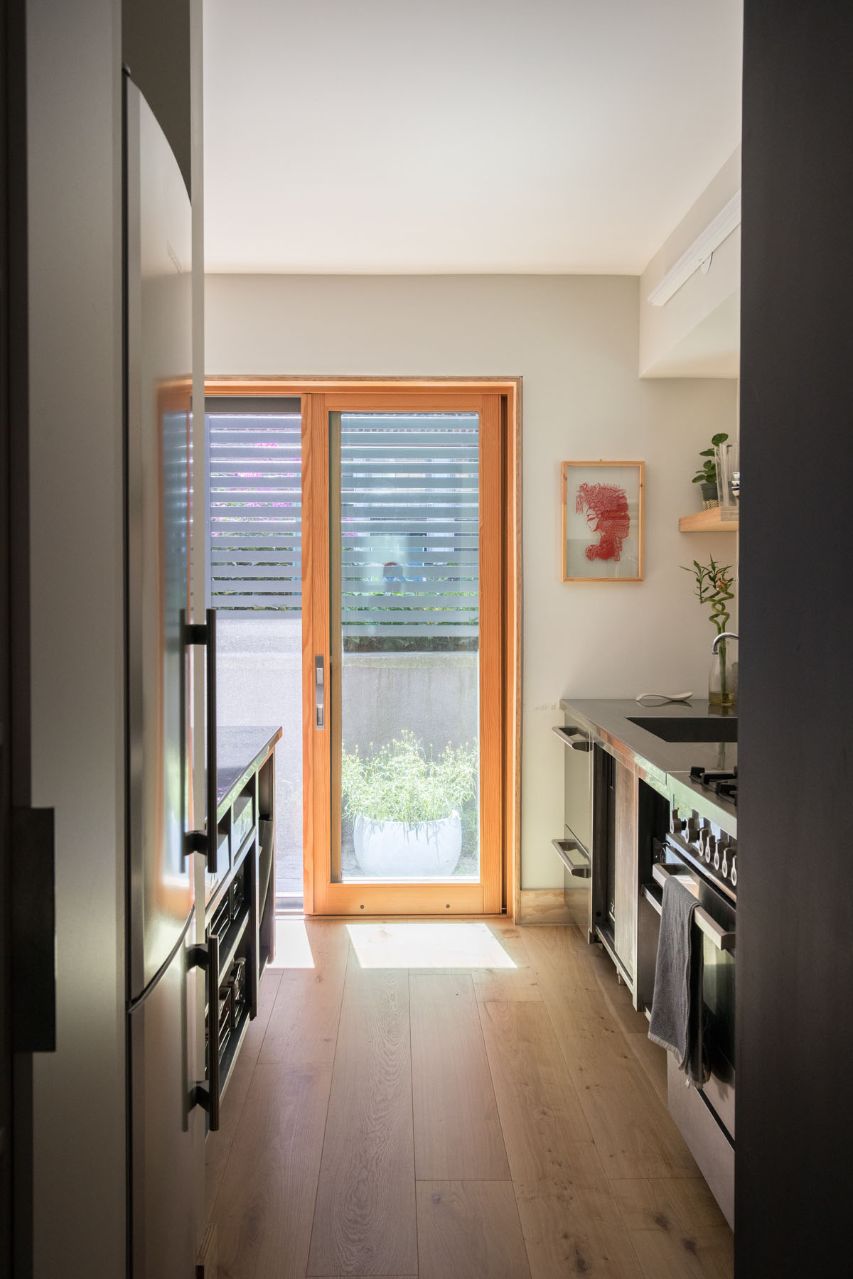 View towards the garden through a wooden framed glass door in a Manhattan townhouse kitchen by Rauch Architecture.
