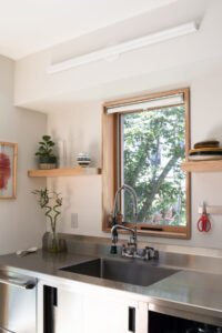 Manhattan townhouse kitchen sink with stainless steel countertop and natural wood floating shelf by Rauch Architecture.