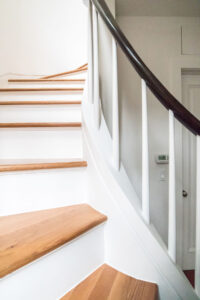Architecturally designed staircase with red oak treads, white risers, and dark handrails, part of Rauch Architecture's Park Slope townhouse renovation.