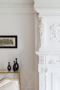 White ornate fireplace mantel with detailed carvings and a framed artwork above, part of Rauch Architecture's Park Slope townhouse renovation.