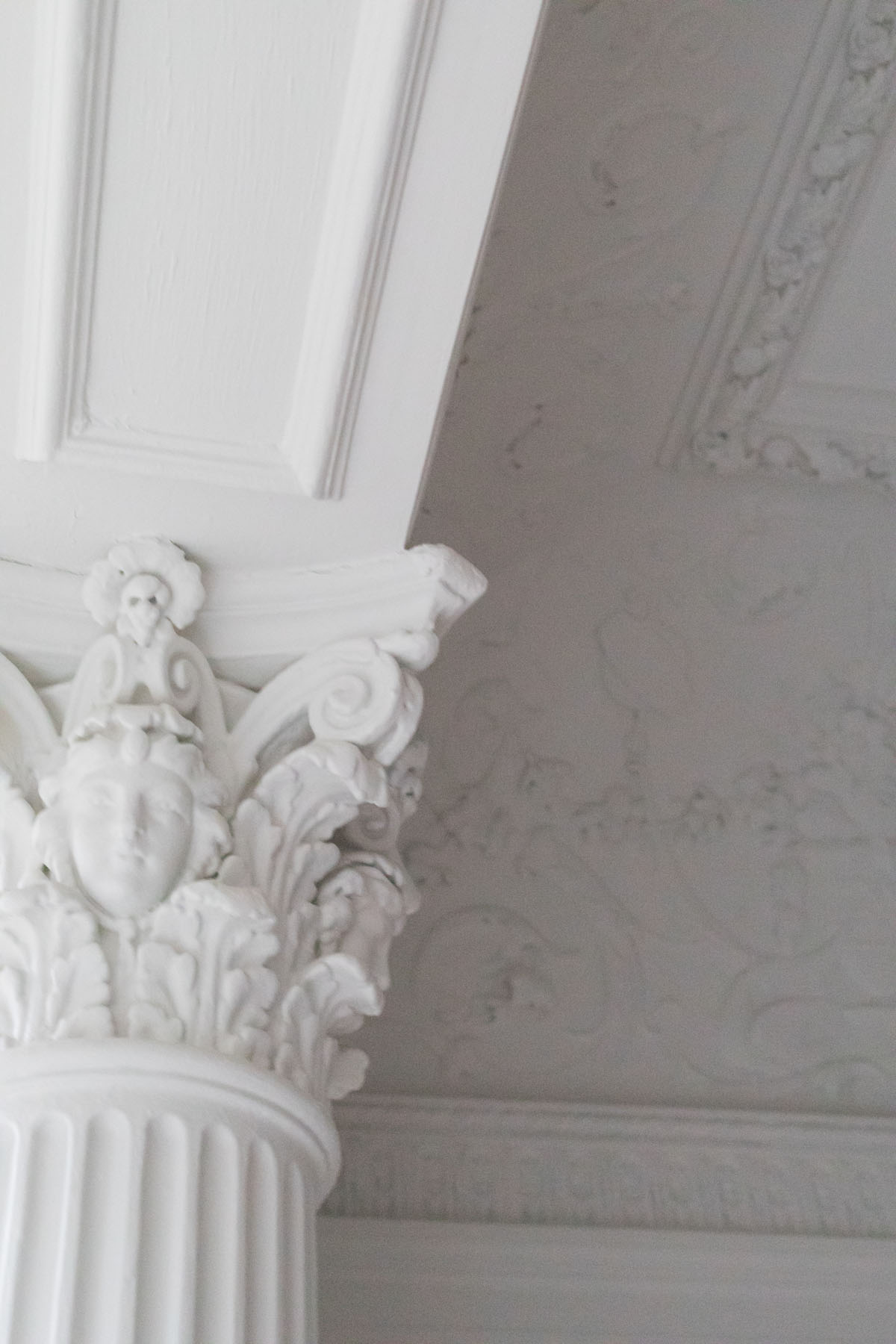 Detail of intricate white Corinthian column capital and ornate ceiling plasterwork in a restored Park Slope townhouse by Rauch Architecture.