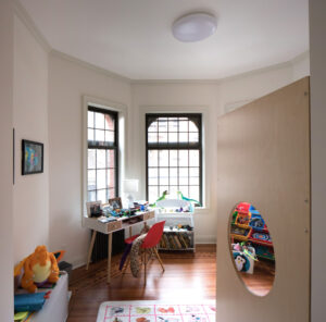 Child's bedroom in a Park Slope townhouse by Rauch Architecture, featuring wooden floors, large windows with black trim, and playful furnishings.