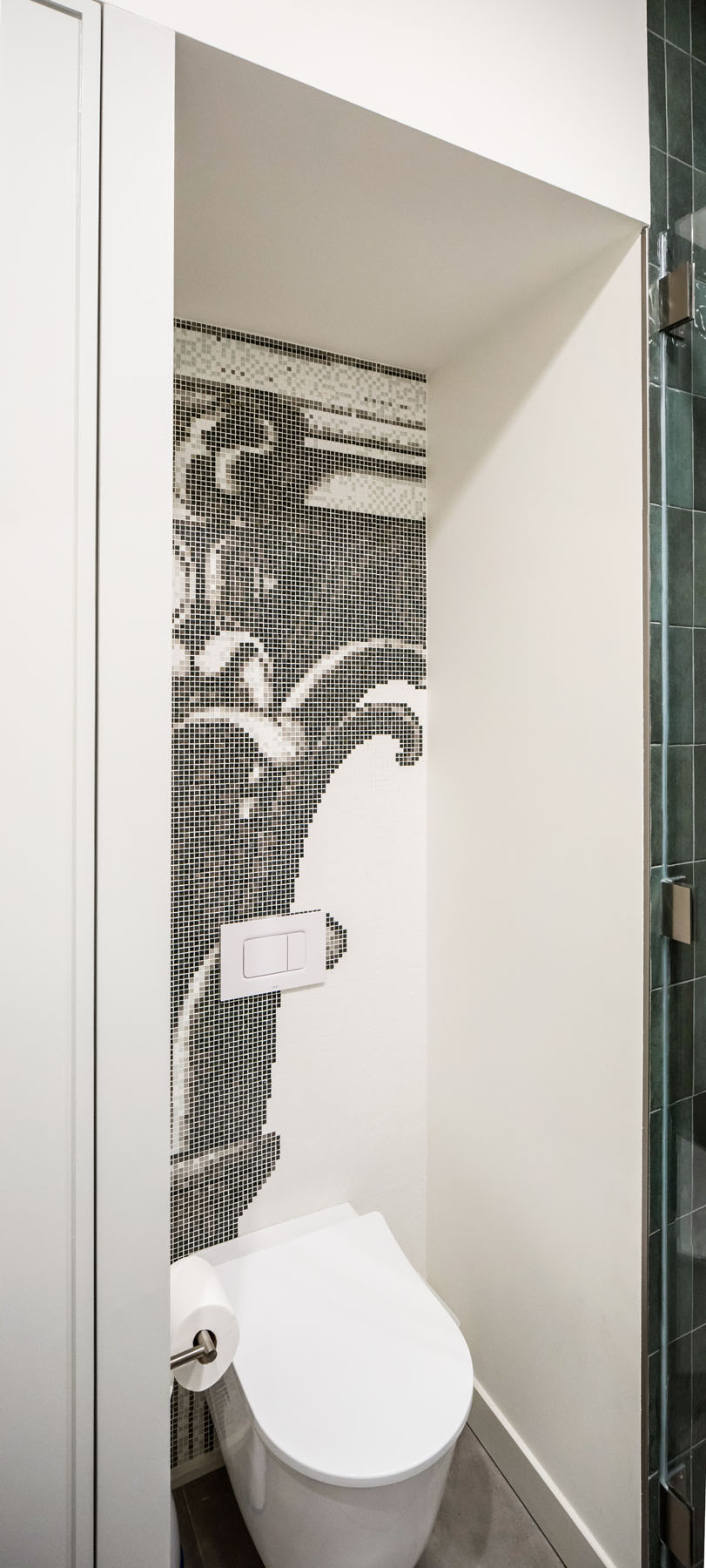 Mosaic tile feature wall in a New York City townhouse WC, depicting Corinthian column detailing, next to a modern toilet and shower with dark green tiles, by Rauch Architecture.