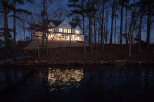 Illuminated lakeside house at dusk designed by Rauch Architecture.