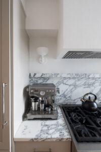 Upper East Side kitchen detail with marble backsplash, espresso machine, gas stove, and contemporary white light fixture designed by Rauch Architecture