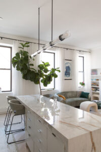 Modern Chelsea, NYC duplex living area with marble kitchen island and grey upholstered seating by Rauch Architecture.