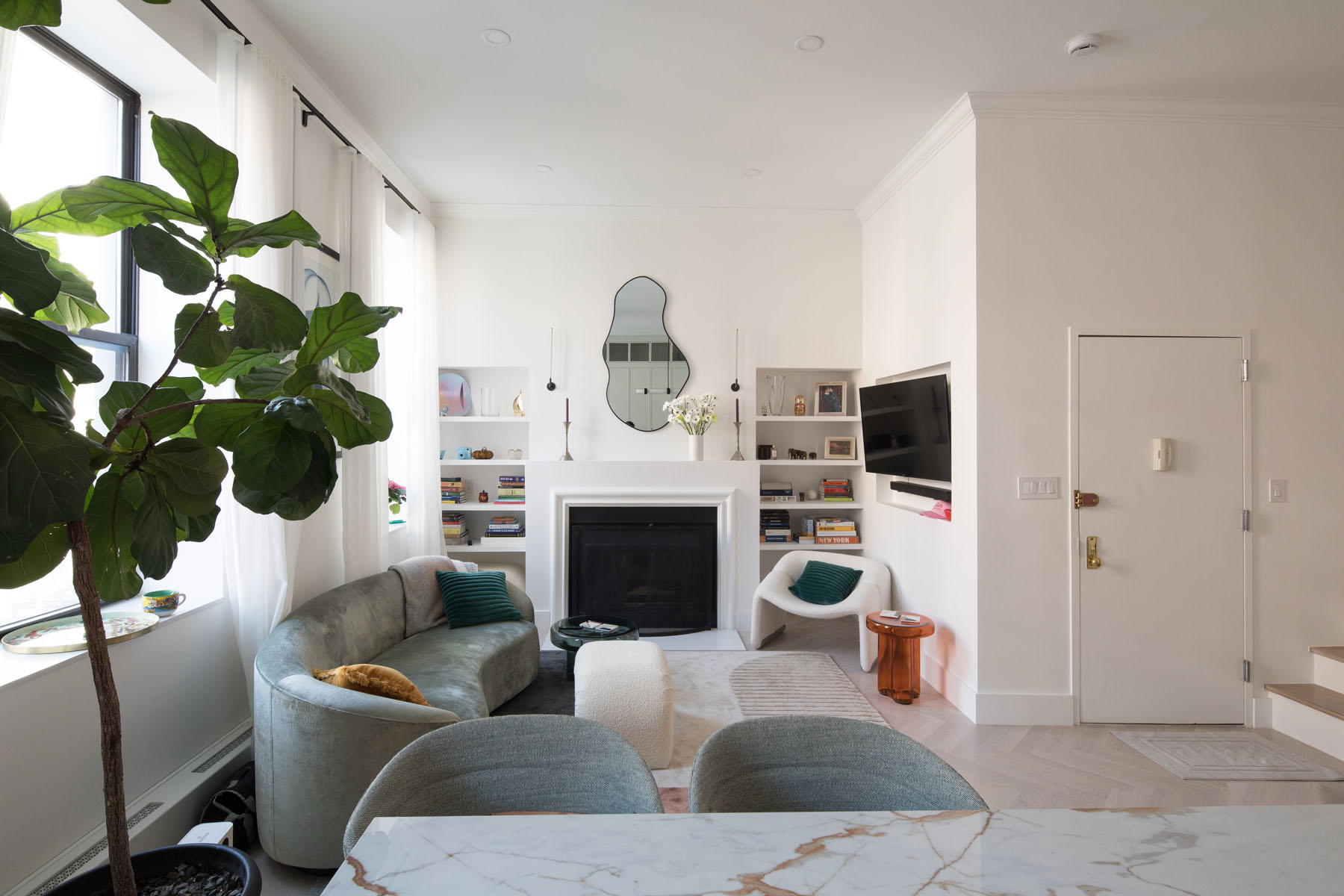 Contemporary living room in Chelsea duplex featuring a marble fireplace, built-in bookshelves, and modern furnishings by Rauch Architecture.