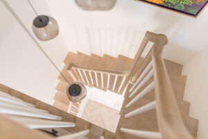 Overhead view of a wooden staircase with modern railings in a Chelsea, NYC duplex renovation by Rauch Architecture.