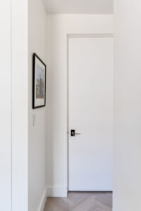 Minimalist corridor with a trimless door and herringbone wood flooring in a Chelsea, NYC duplex by Rauch Architecture.