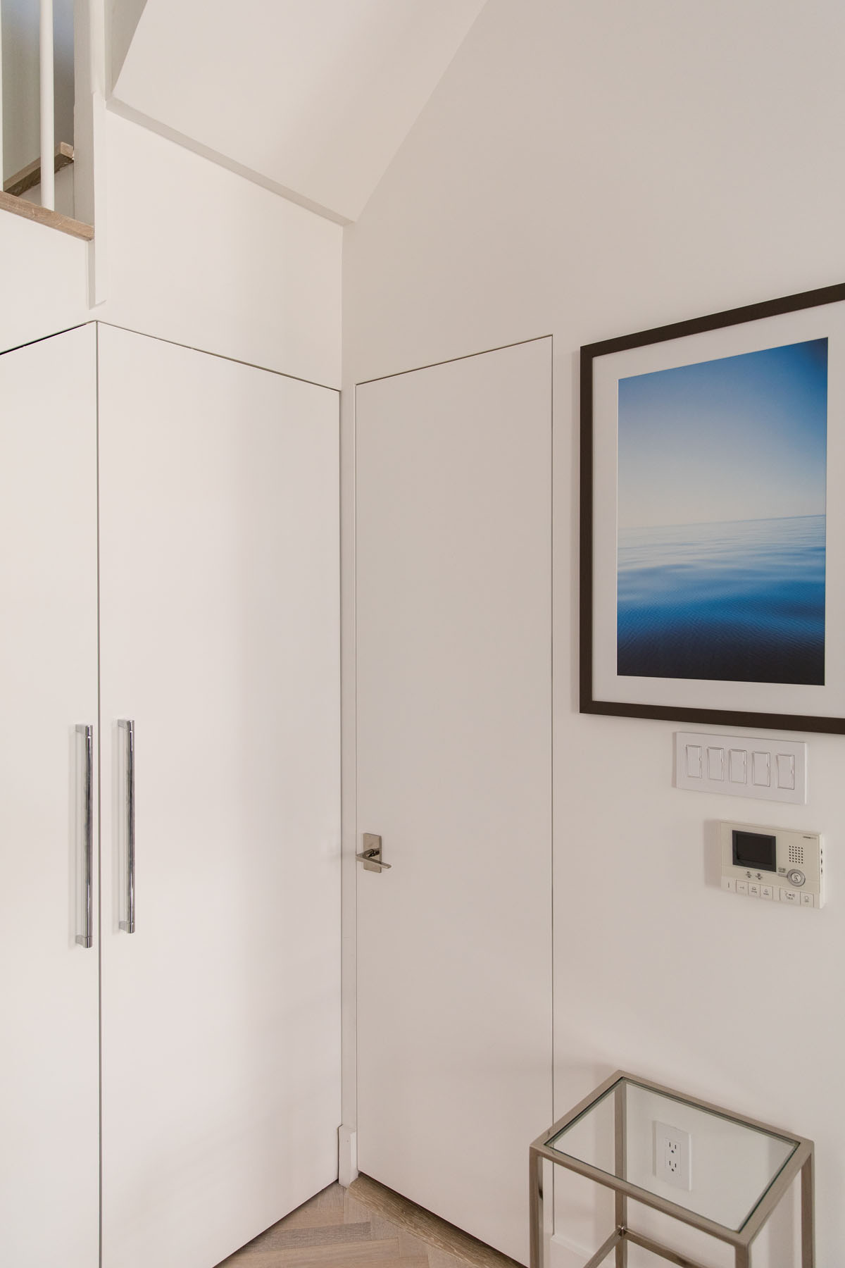 Minimalist detailing with a trimless door and herringbone wood flooring in a Chelsea, NYC duplex by Rauch Architecture.