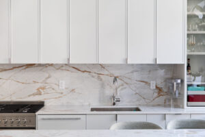 Close-up of white slim shaker kitchen cabinets with marble backsplash in a Chelsea, NYC duplex by Rauch Architecture.