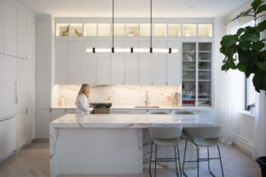 Modern kitchen with white slim shaker cabinets, marble island, and backsplash in a Chelsea, NYC duplex by Rauch Architecture.