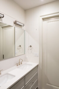 Modern bathroom vanity with marble countertop, undermount sink, and wall-mounted mirror flanked by sconces